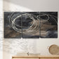 Three-panel canvas wall art featuring dark swirling abstract motion, displayed in a minimalist living room above a console table.