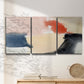 Three-panel canvas wall art featuring playful abstract watercolor shapes, displayed in a minimalist living room above a console table.