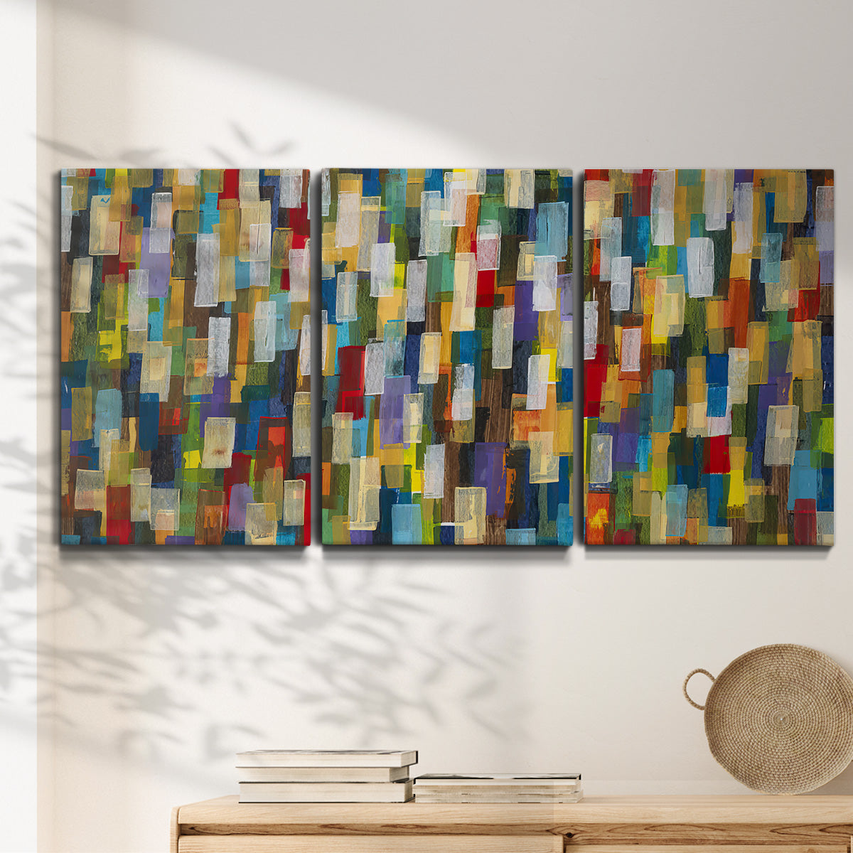 Three-panel canvas wall art featuring colorful confetti style abstraction, displayed in a minimalist living room above a console table.