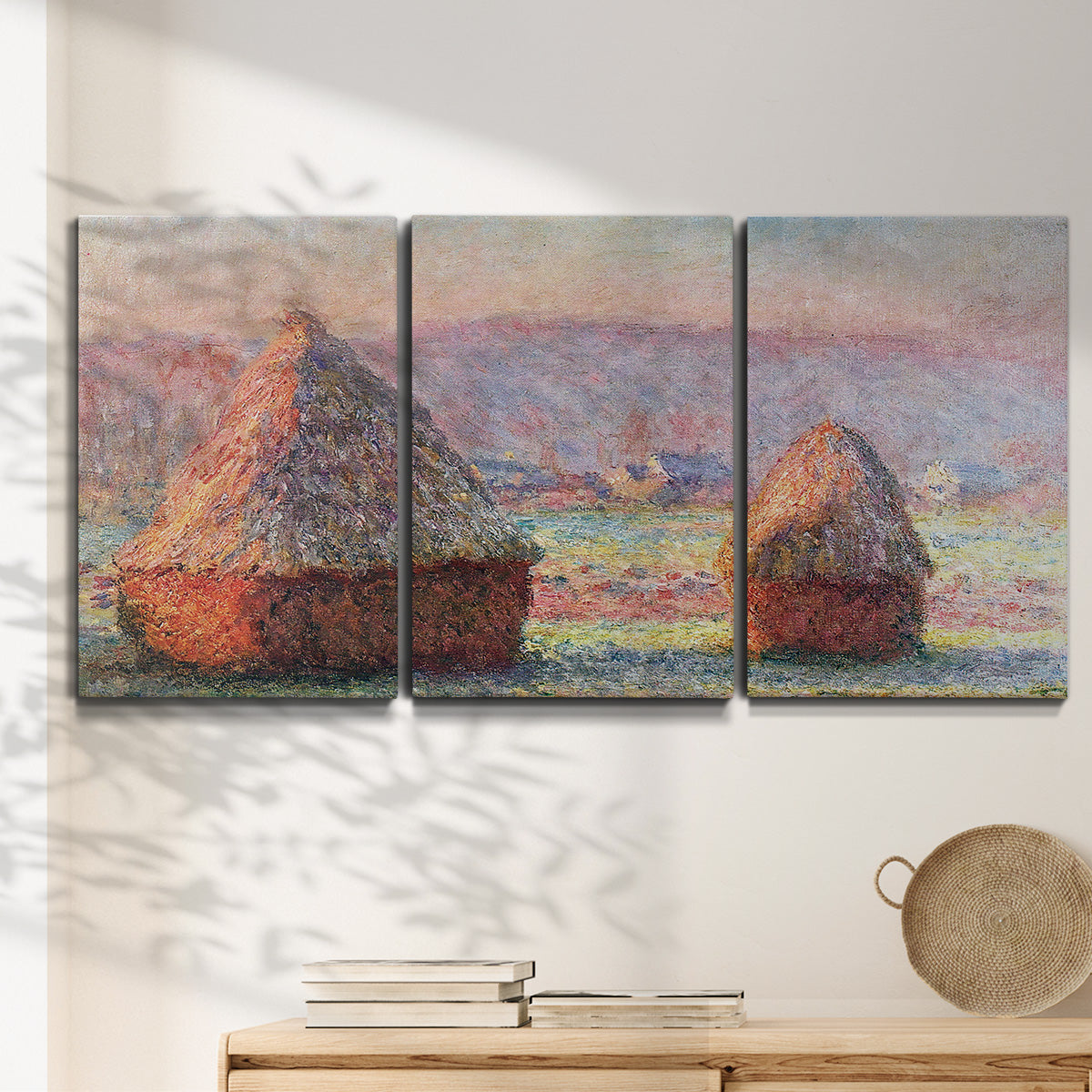 Three-panel canvas wall art featuring winter grainstacks glowing at sunset, displayed in a minimalist living room above a console table.
