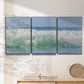 Three-panel canvas wall art featuring coastal waves breaking ashore, displayed in a minimalist living room above a console table.