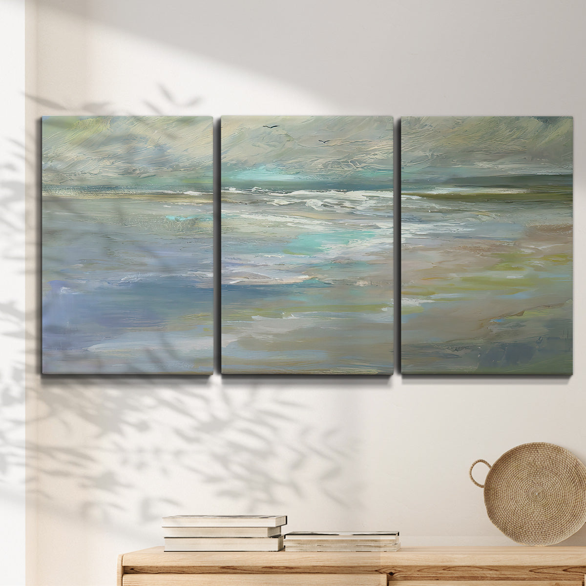 Three-panel canvas wall art featuring soft coastal beach light landscape, displayed in a minimalist living room above a console table.