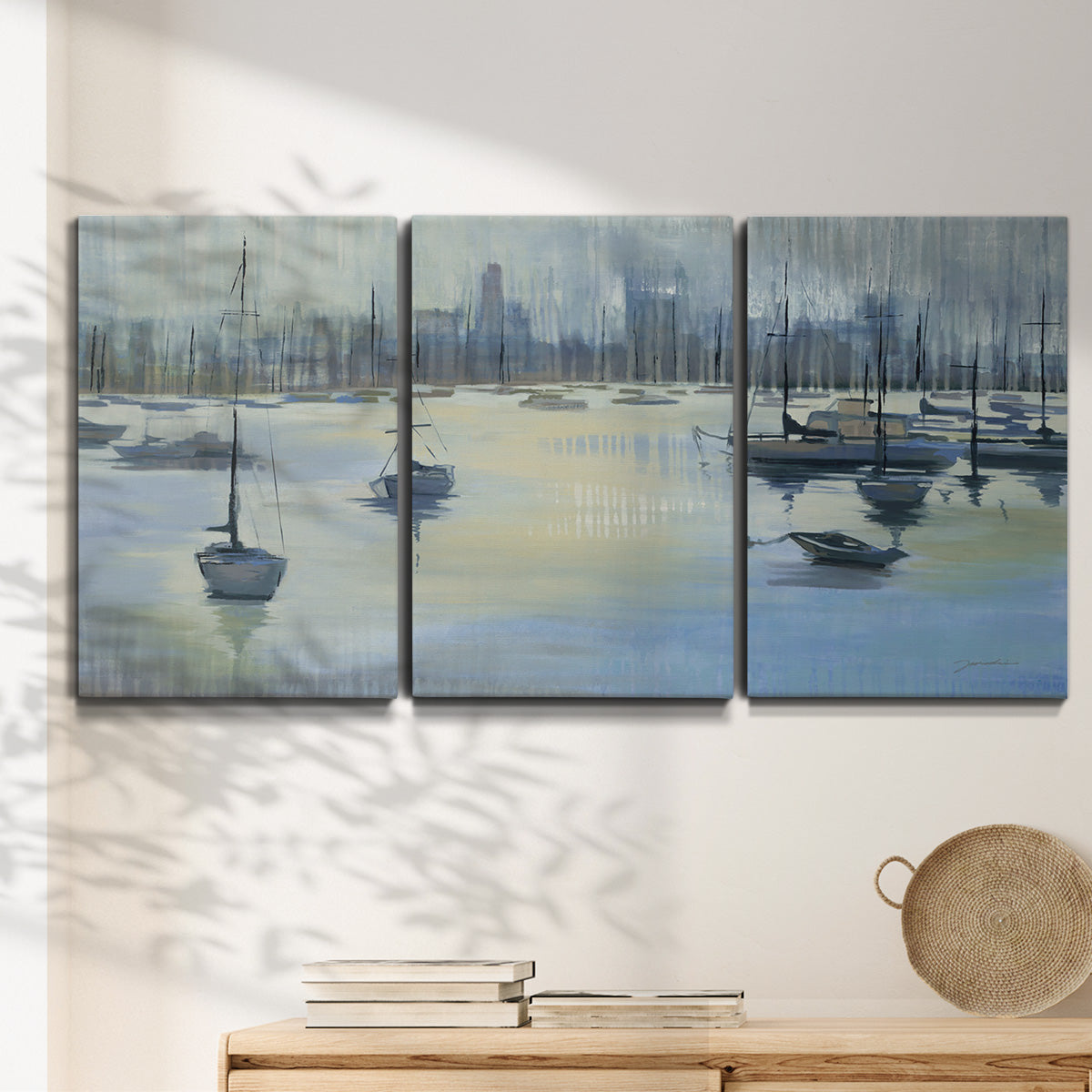 Three-panel canvas wall art featuring anchored boats near shoreline, displayed in a minimalist living room above a console table.