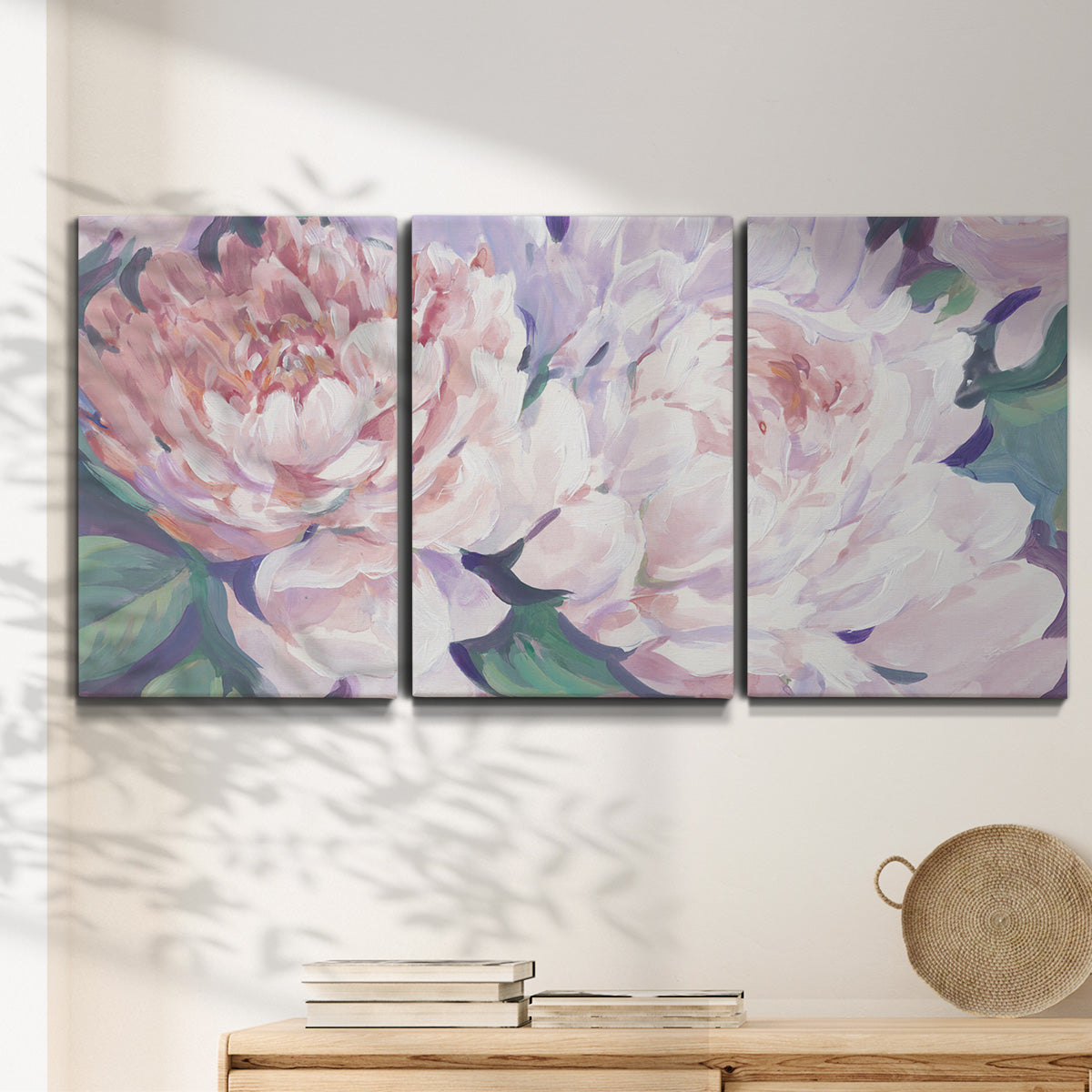 Three-panel canvas wall art featuring soft pink peonies in bloom, displayed in a minimalist living room above a console table.