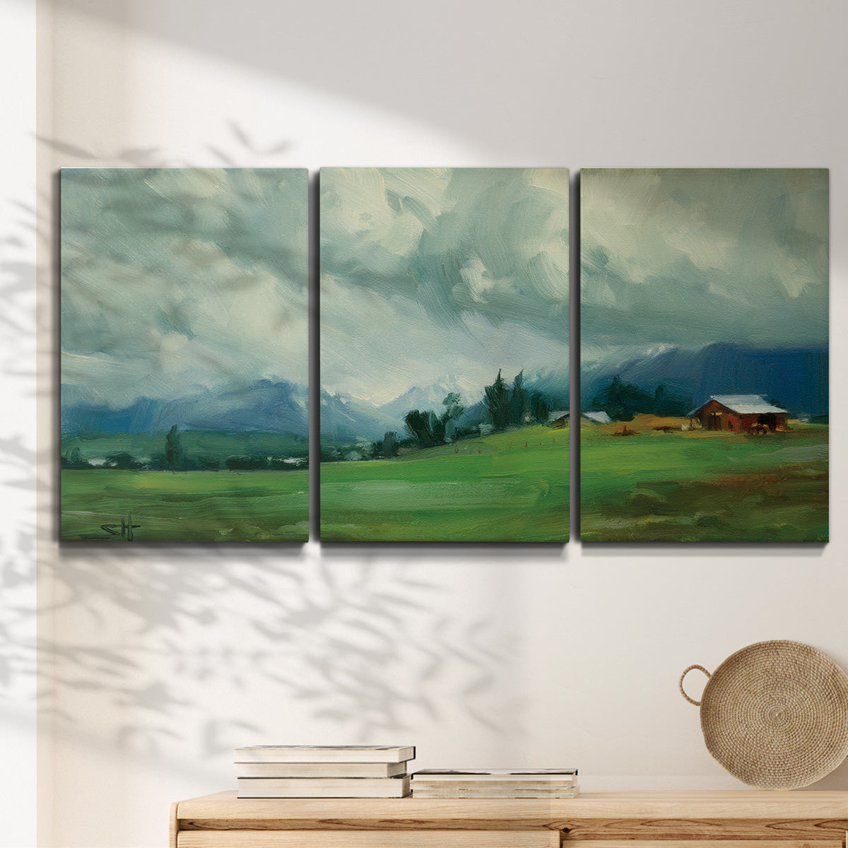 Three-panel canvas wall art featuring wide pastoral valley landscape, displayed in a minimalist living room above a console table.