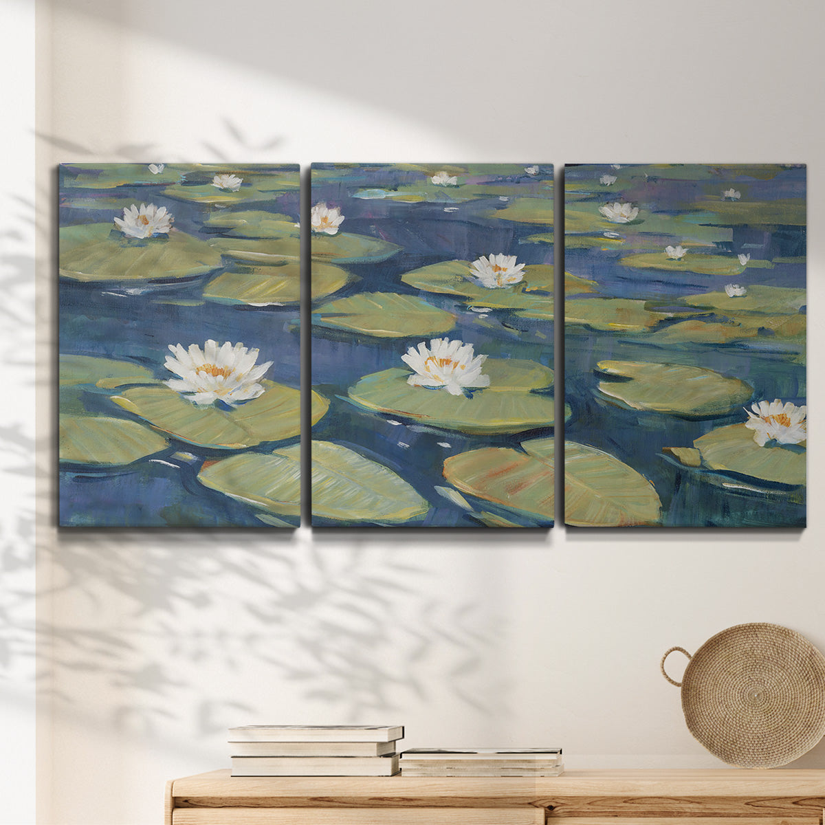 Three-panel canvas wall art featuring water lilies floating on pond, displayed in a minimalist living room above a console table.