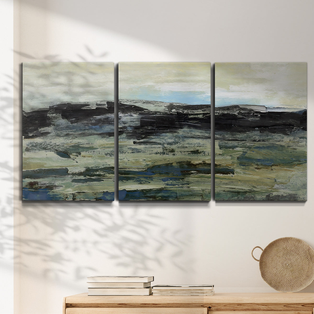 Three-panel canvas wall art featuring muted abstract landscape study, displayed in a minimalist living room above a console table.