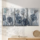 Three-panel canvas wall art featuring indigo floral abstraction, displayed in a minimalist living room above a console table.