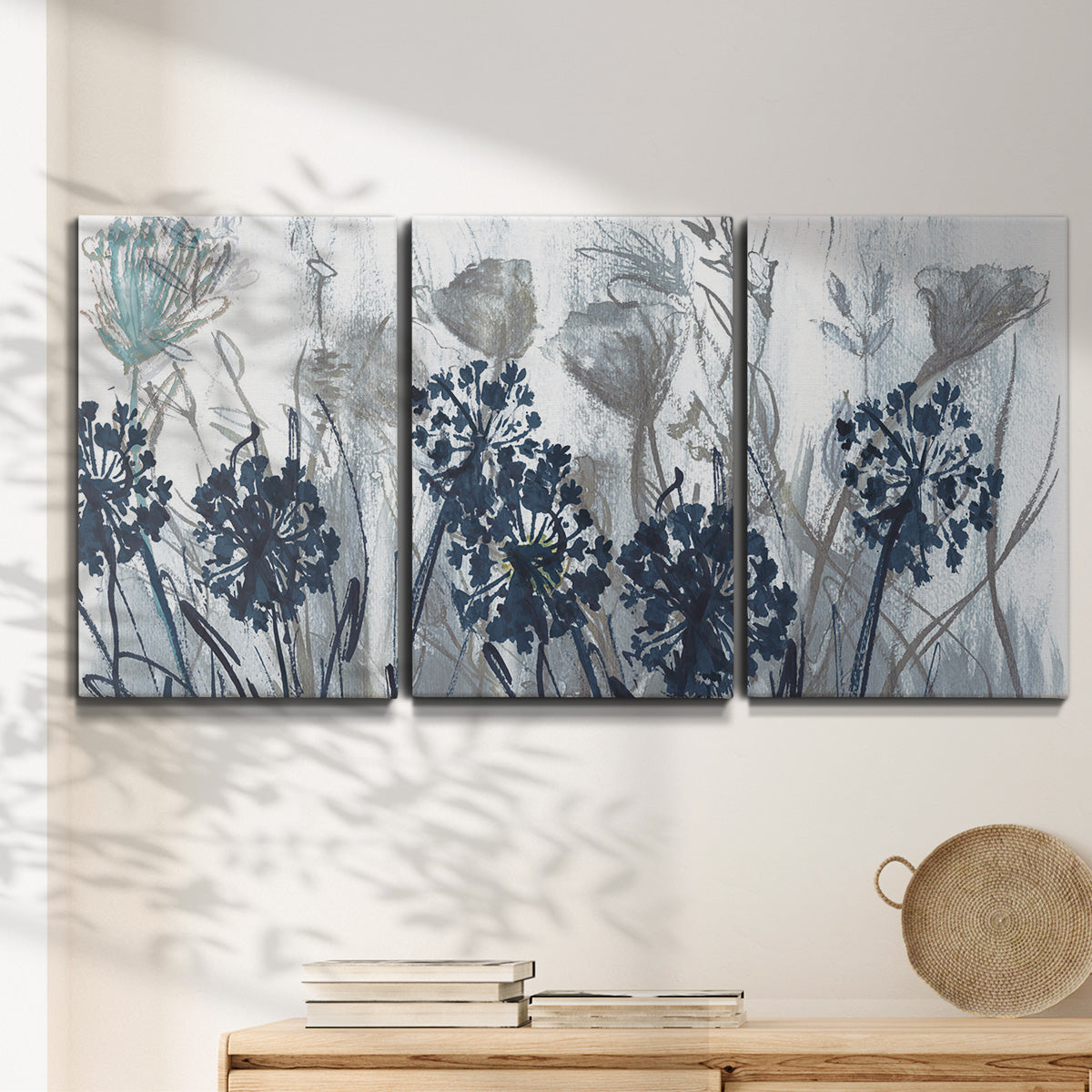 Three-panel canvas wall art featuring indigo floral abstraction, displayed in a minimalist living room above a console table.