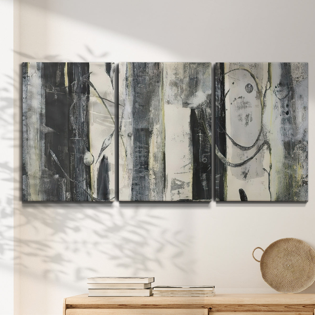 Three-panel canvas wall art featuring vertical abstract tree forms, displayed in a minimalist living room above a console table.
