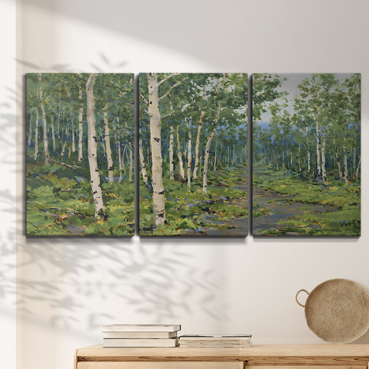Three-panel canvas wall art featuring woodland forest scene with tall trees, displayed in a minimalist living room above a console table.