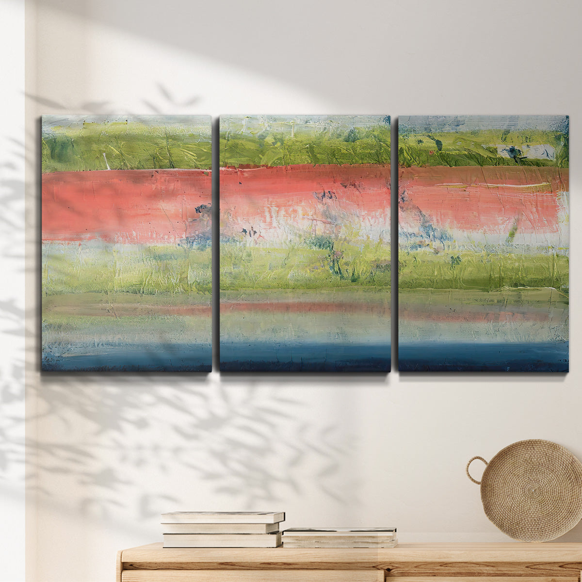 Three-panel canvas wall art featuring layered abstract color banding, displayed in a minimalist living room above a console table.