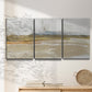 Three-panel canvas wall art featuring golden hour light over landscape, displayed in a minimalist living room above a console table.