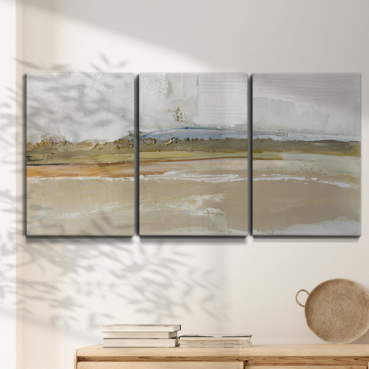 Three-panel canvas wall art featuring golden hour light over landscape, displayed in a minimalist living room above a console table.