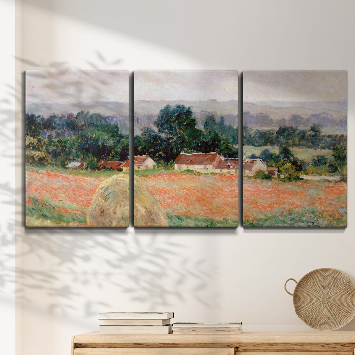 Three-panel canvas wall art featuring haystacks arranged in rural field, displayed in a minimalist living room above a console table.