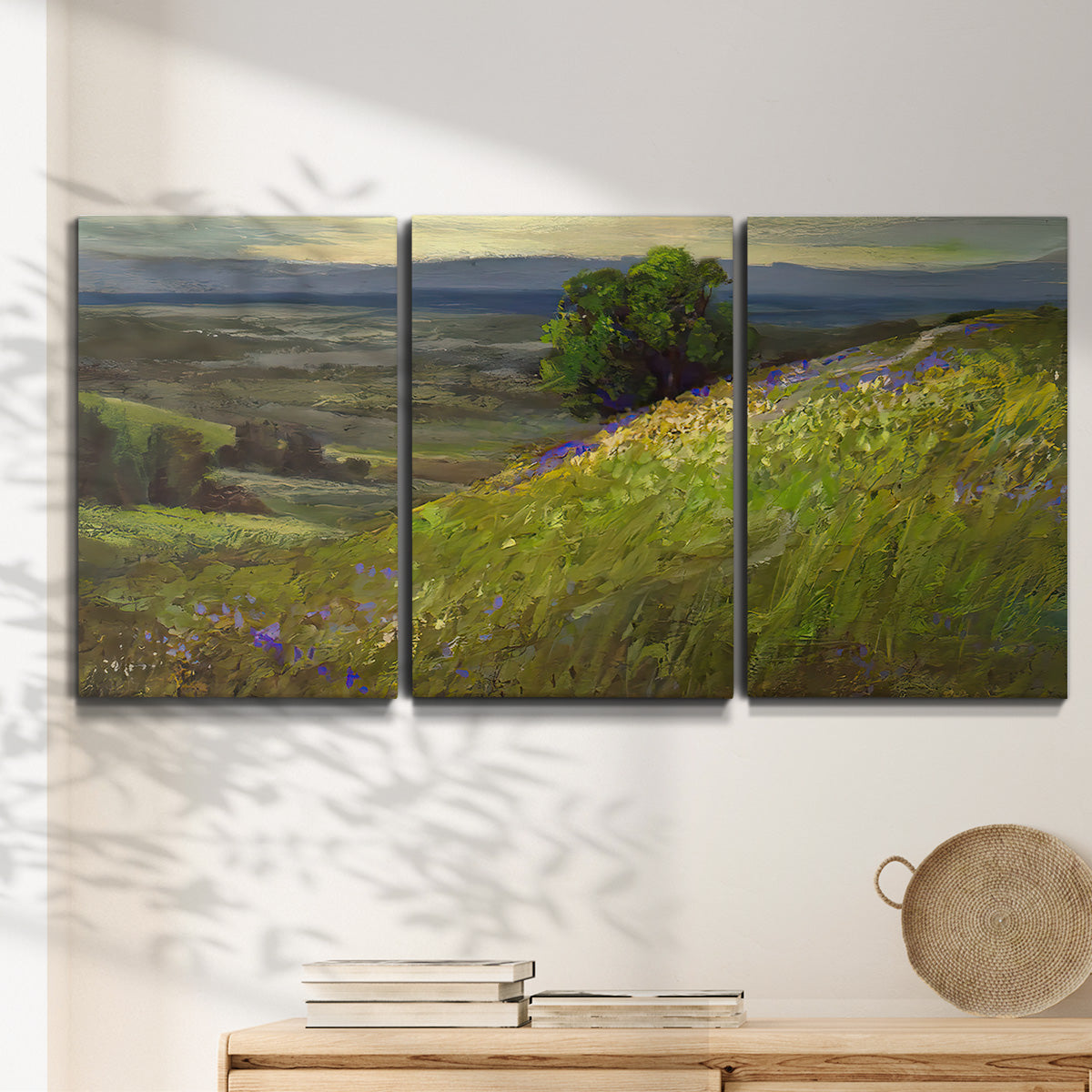 Three-panel canvas wall art featuring winding path through rolling hills, displayed in a minimalist living room above a console table.