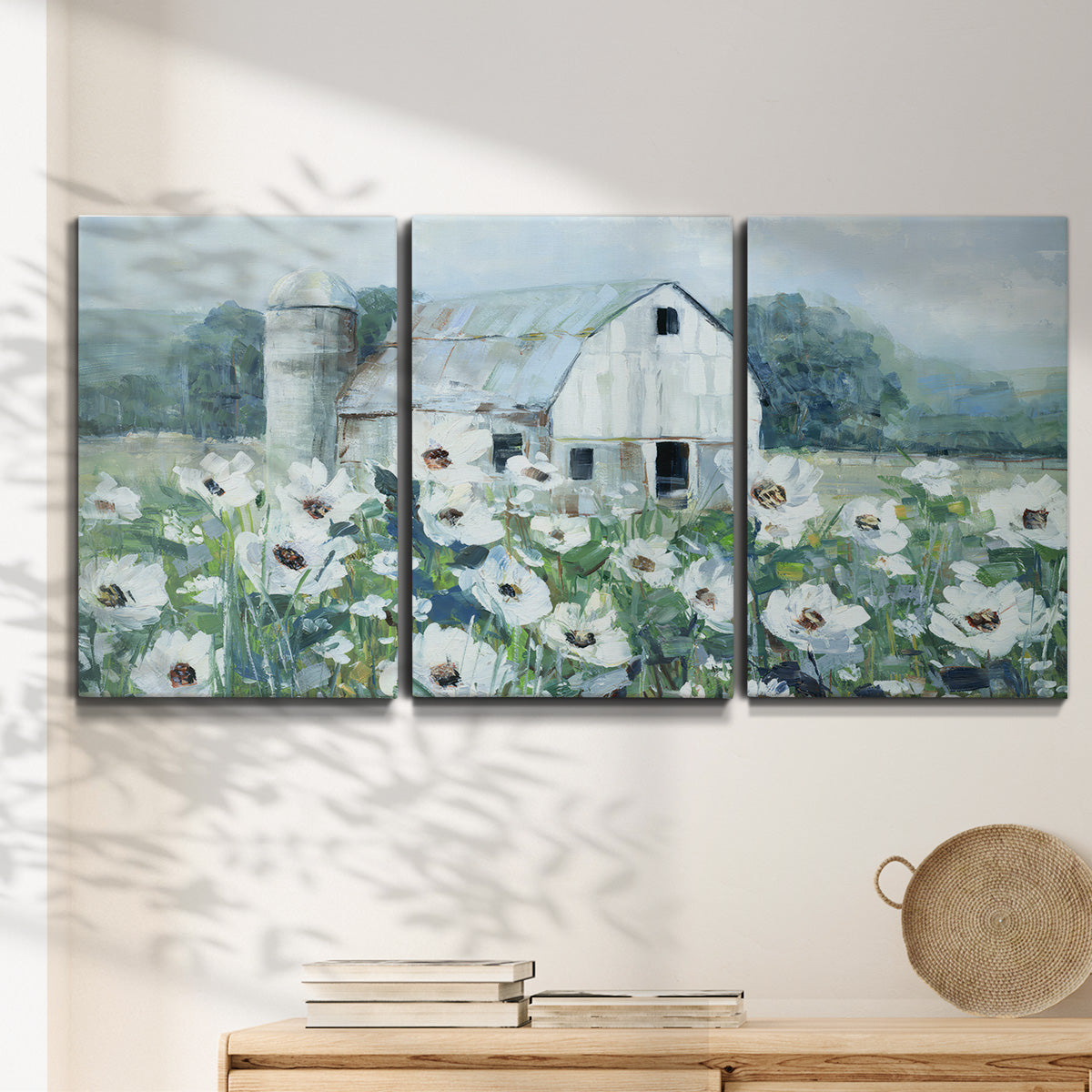 Three-panel canvas wall art featuring pastoral farmland with open fields, displayed in a minimalist living room above a console table.