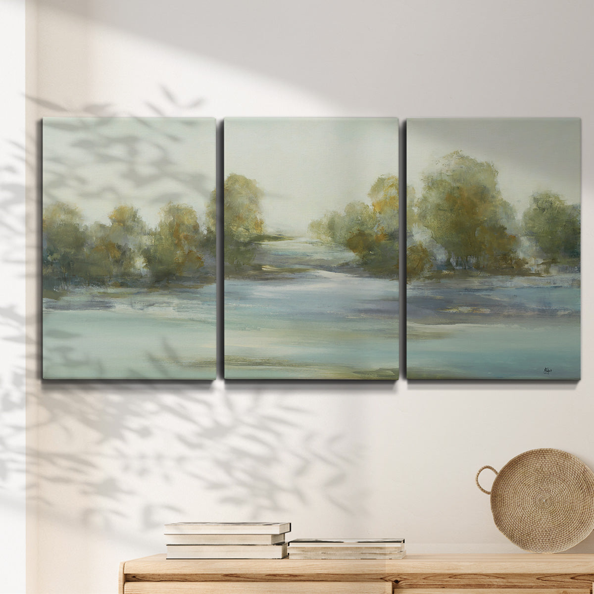 Three-panel canvas wall art featuring calming scenic landscape view, displayed in a minimalist living room above a console table.