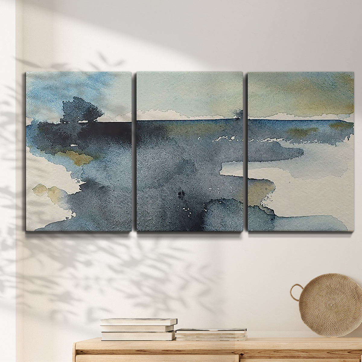 Three-panel canvas wall art featuring abstract watercolor with upward motion, displayed in a minimalist living room above a console table.