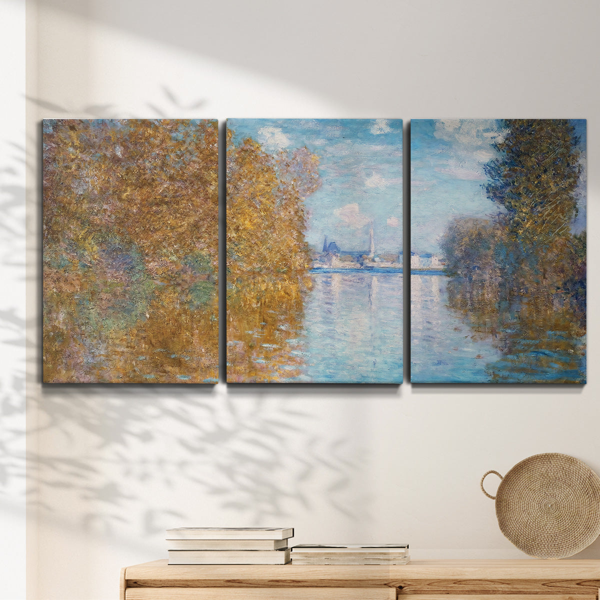 Three-panel canvas wall art featuring autumn landscape with glowing foliage, displayed in a minimalist living room above a console table.