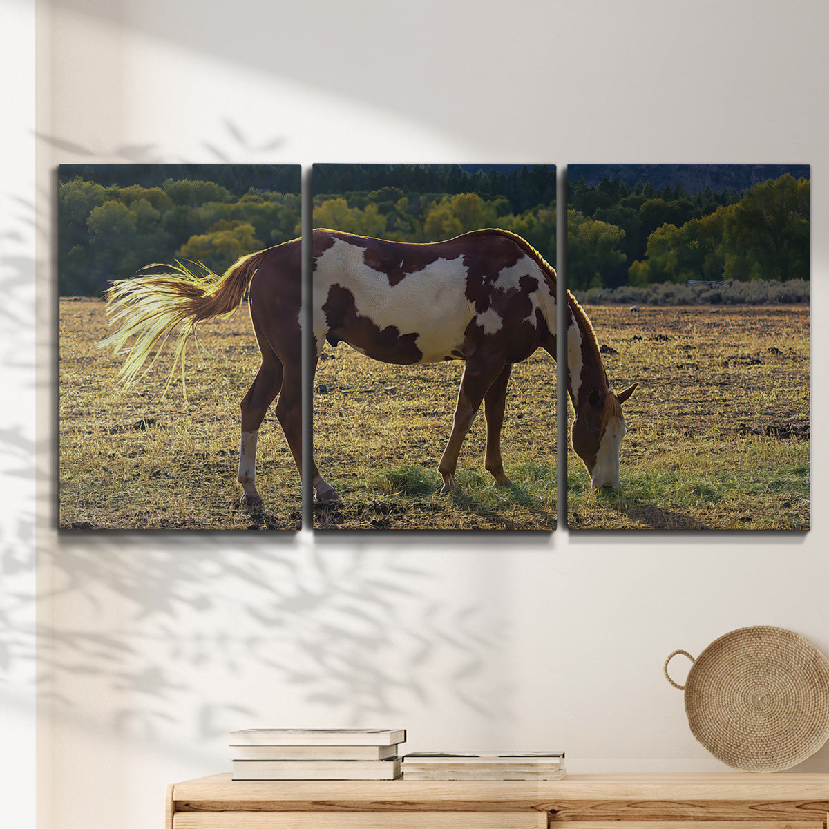 Three-panel canvas wall art featuring horses standing near farmhouse, displayed in a minimalist living room above a console table.