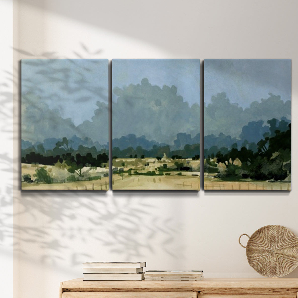 Three-panel canvas wall art featuring rural farmland landscape in watercolor, displayed in a minimalist living room above a console table.