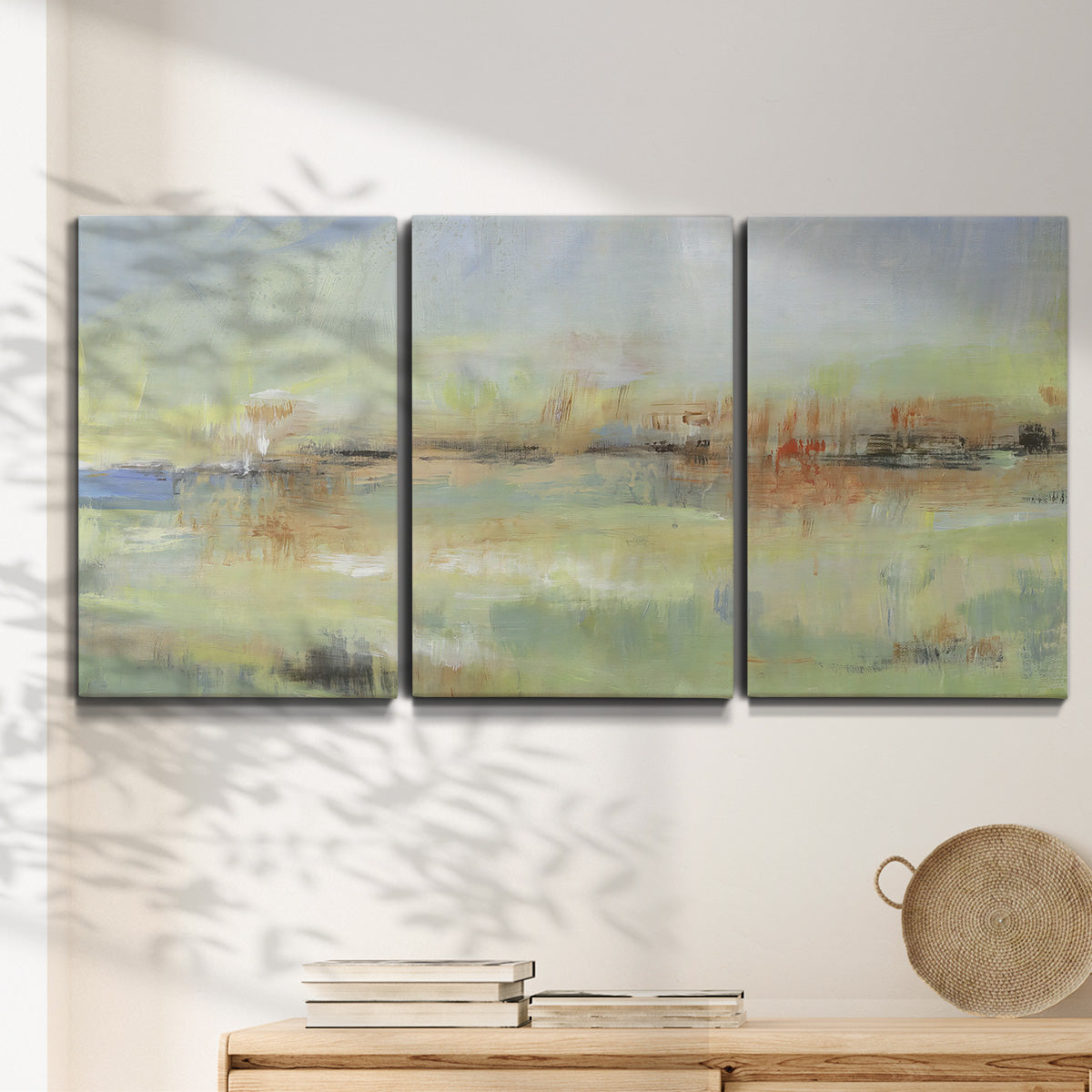 Three-panel canvas wall art featuring layered abstract transitional textures, displayed in a minimalist living room above a console table.