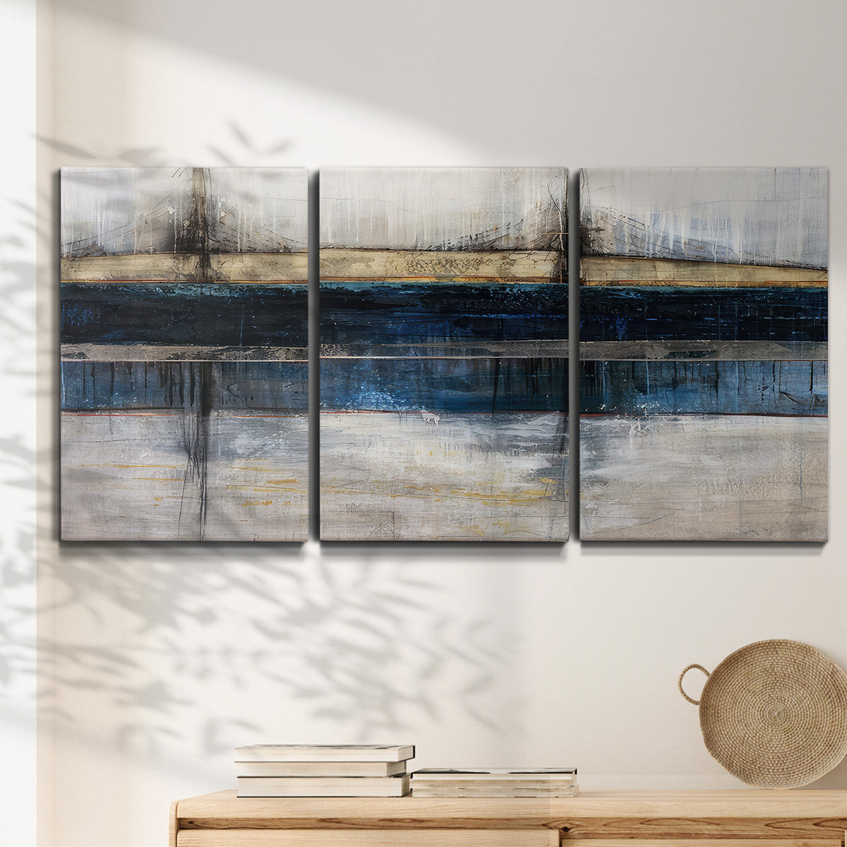Three-panel canvas wall art featuring abstract blue urban composition, displayed in a minimalist living room above a console table.