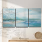 Three-panel canvas wall art featuring sunset silhouette over coastal water, displayed in a minimalist living room above a console table.
