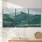 Three-panel canvas wall art featuring muted mountain range in grey tones, displayed in a minimalist living room above a console table.