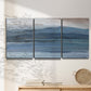 Three-panel canvas wall art featuring wide lake with distant shoreline, displayed in a minimalist living room above a console table.
