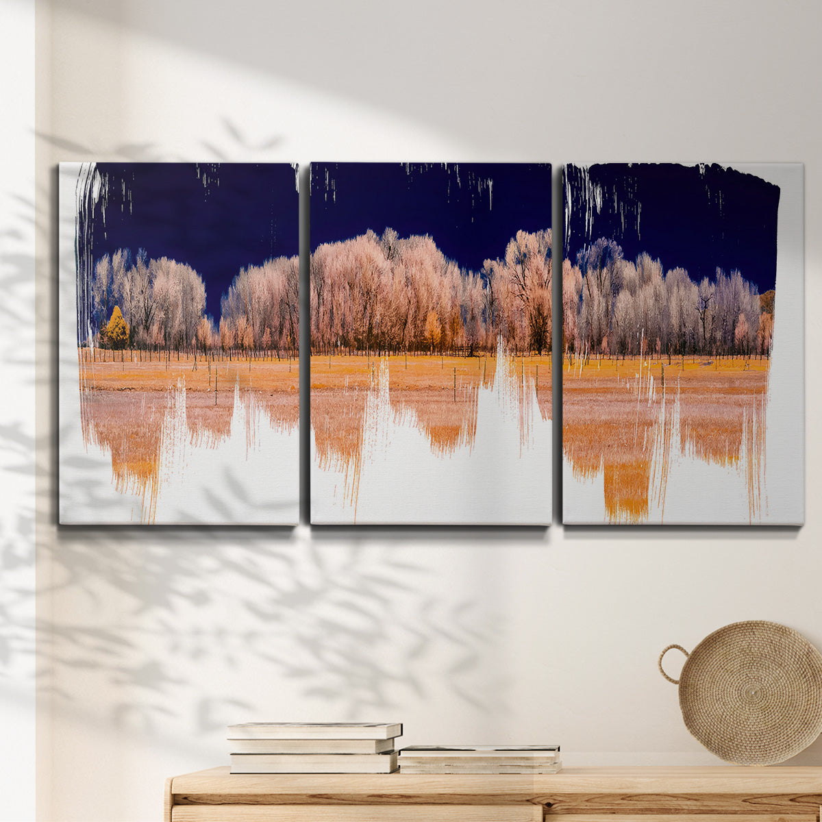 Three-panel canvas wall art featuring panoramic treeline landscape photograph, displayed in a minimalist living room above a console table.