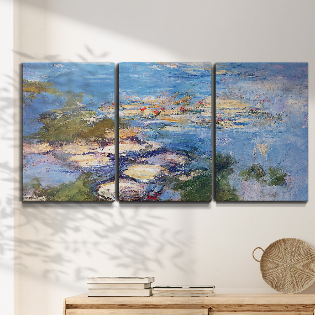 Three-panel canvas wall art featuring water lilies in blue and gold, displayed in a minimalist living room above a console table.