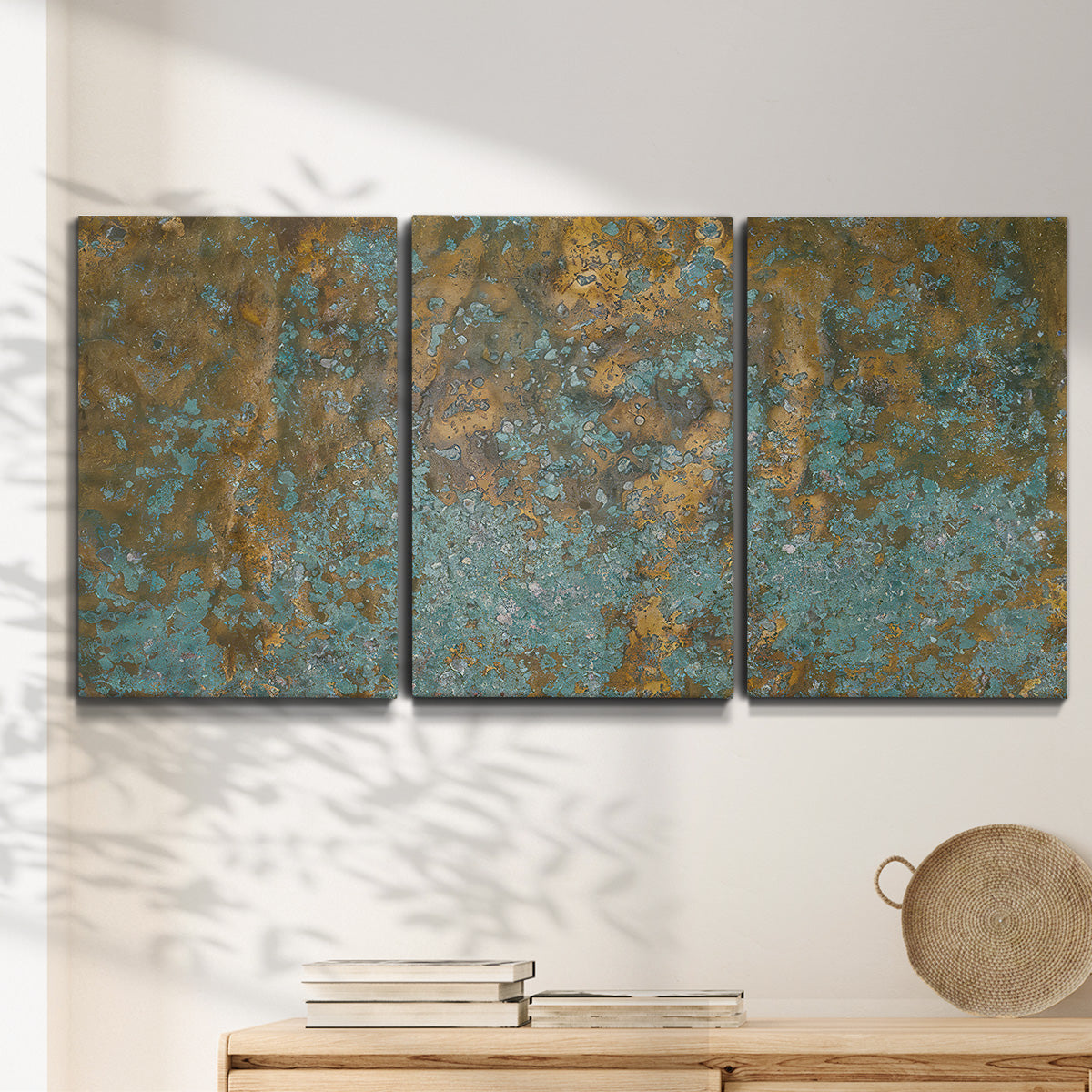 Three-panel canvas wall art featuring earthy copper toned abstract, displayed in a minimalist living room above a console table.
