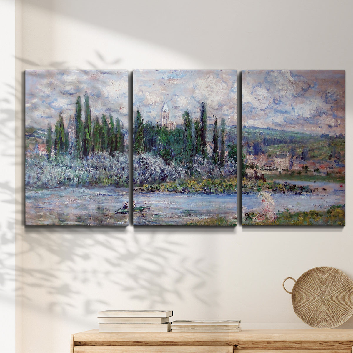 Three-panel canvas wall art featuring summer village view along river, displayed in a minimalist living room above a console table.