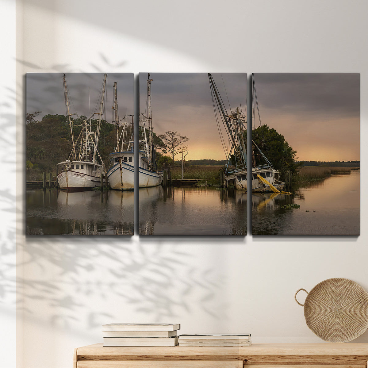 Three-panel canvas wall art featuring fishing trawlers on working harbor, displayed in a minimalist living room above a console table.
