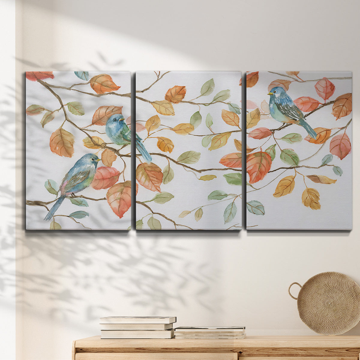 Three-panel canvas wall art featuring decorative bird trio illustration, displayed in a minimalist living room above a console table.