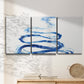 Three-panel canvas wall art featuring indigo abstract vapor watercolor, displayed in a minimalist living room above a console table.