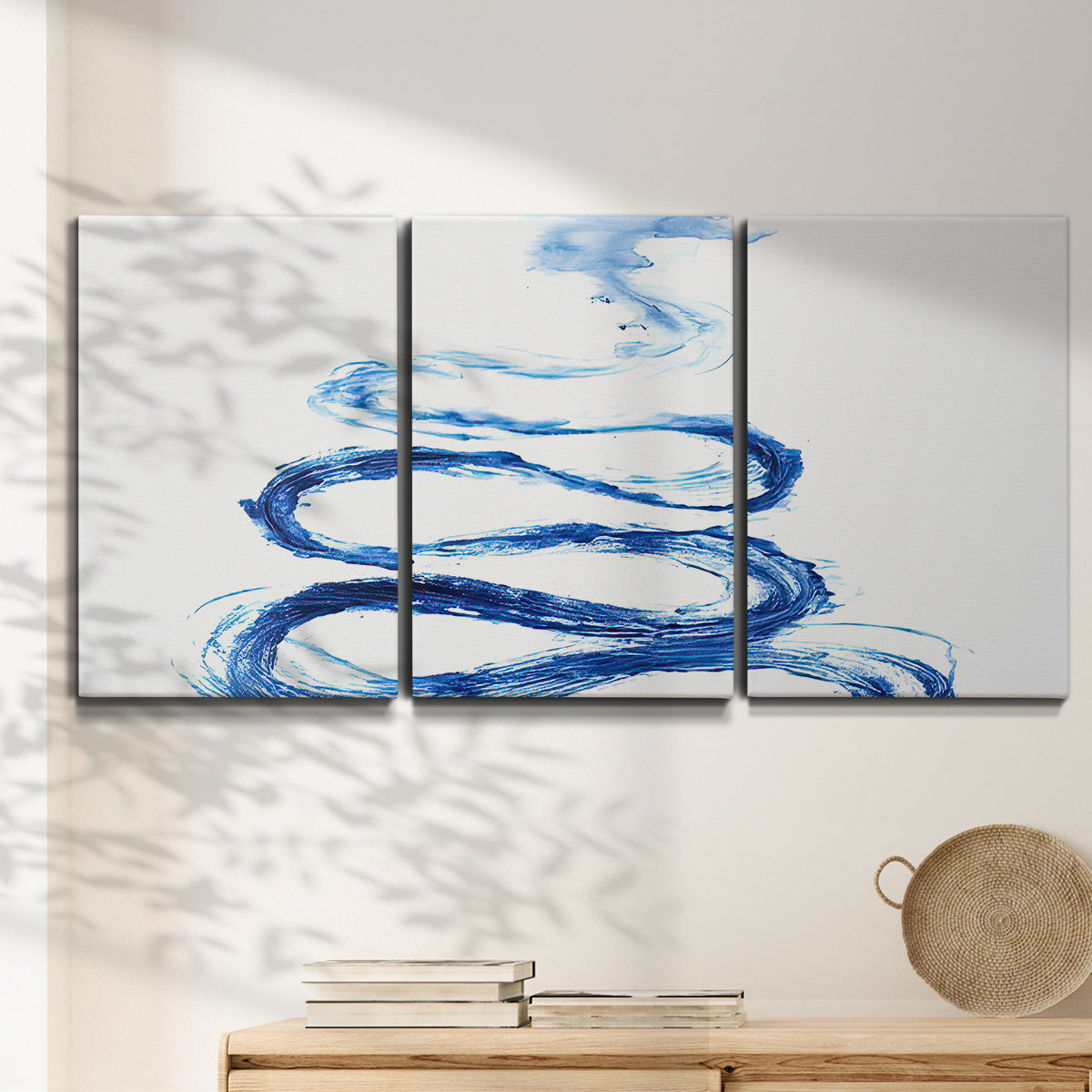 Three-panel canvas wall art featuring indigo abstract vapor watercolor, displayed in a minimalist living room above a console table.