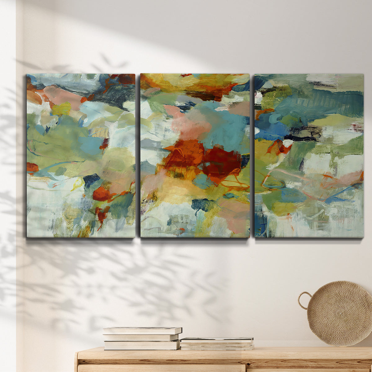 Three-panel canvas wall art featuring celebratory abstract color movement, displayed in a minimalist living room above a console table.