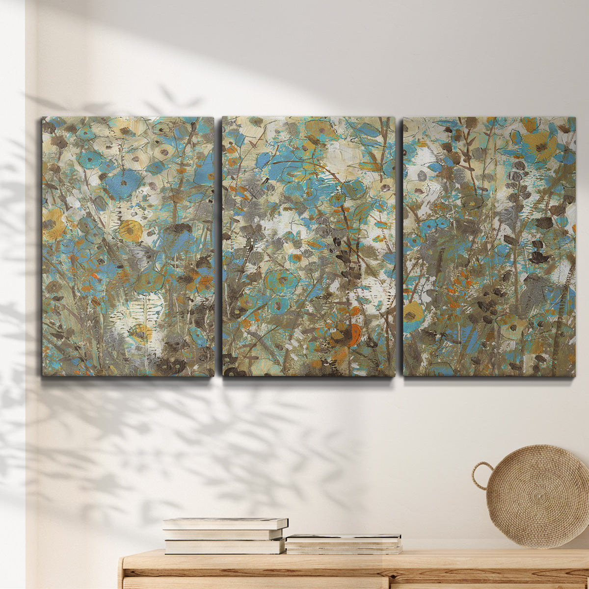 Three-panel canvas wall art featuring abstract flowering vine pattern, displayed in a minimalist living room above a console table.