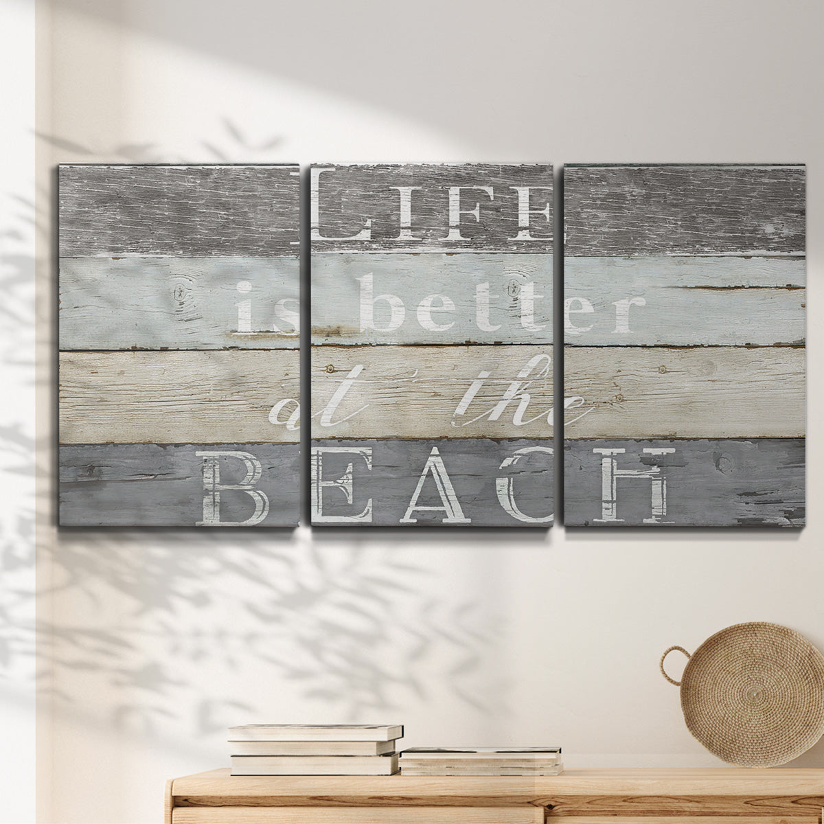 Three-panel canvas wall art featuring beach themed typography design, displayed in a minimalist living room above a console table.