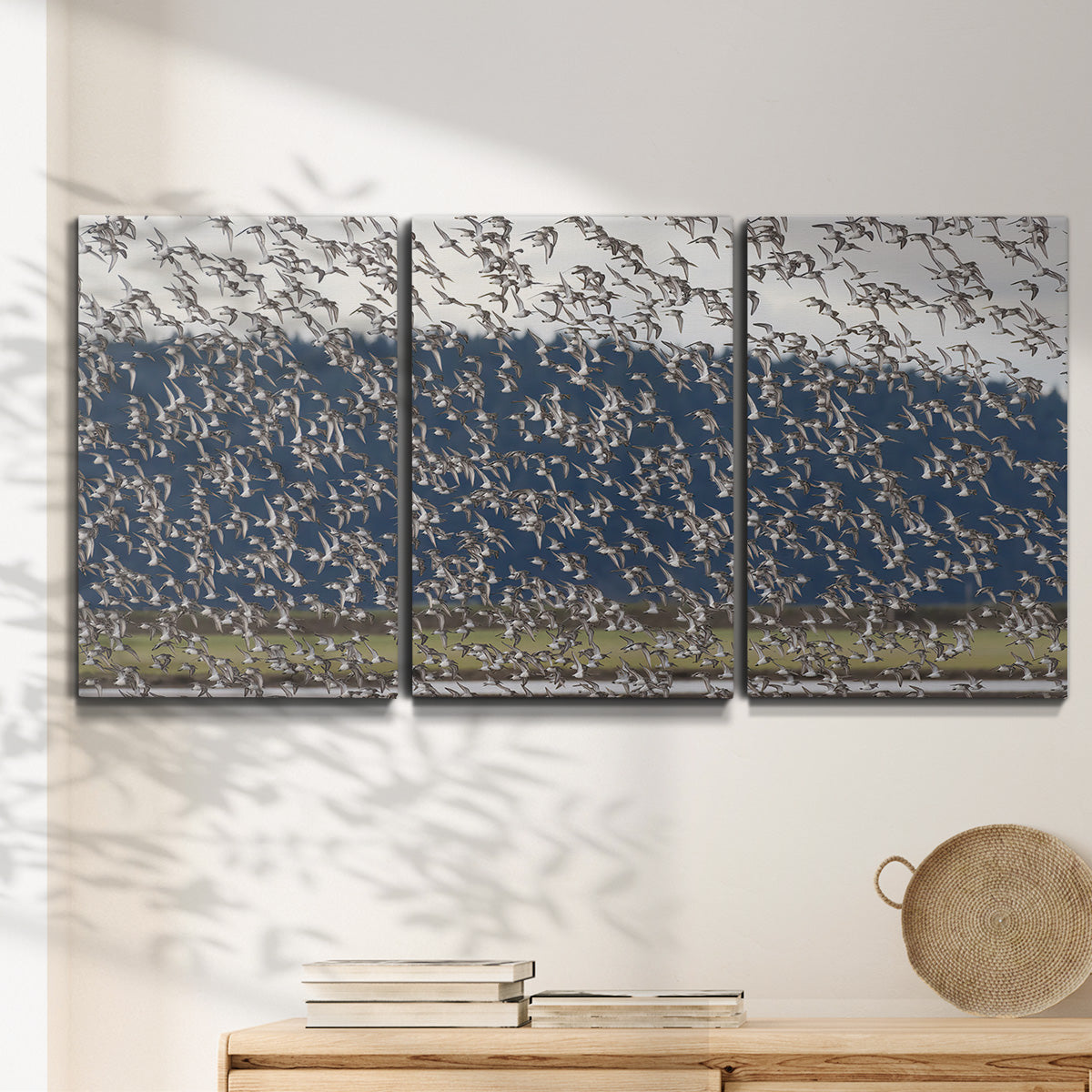 Three-panel canvas wall art featuring group of animals in open field, displayed in a minimalist living room above a console table.