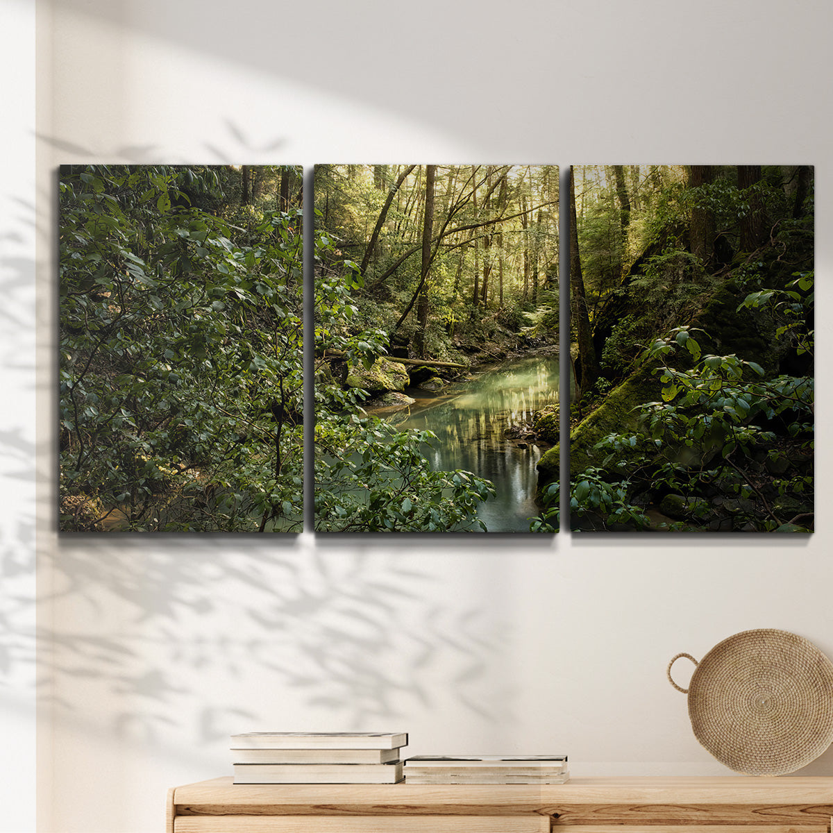 Three-panel canvas wall art featuring sun filtered woodland photograph, displayed in a minimalist living room above a console table.
