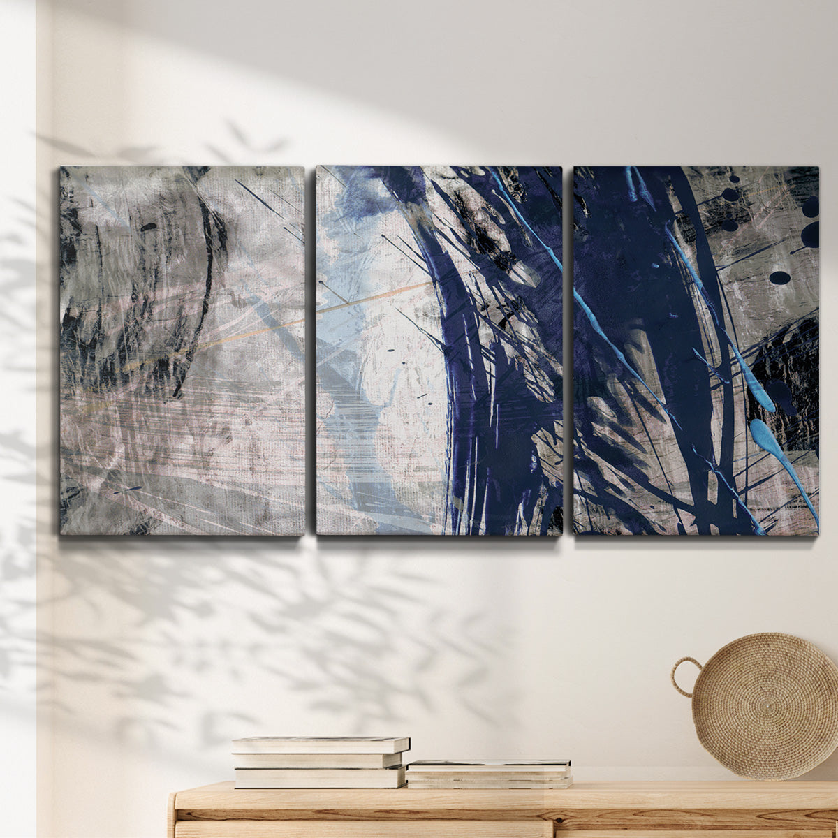 Three-panel canvas wall art featuring layered blue abstract texture, displayed in a minimalist living room above a console table.