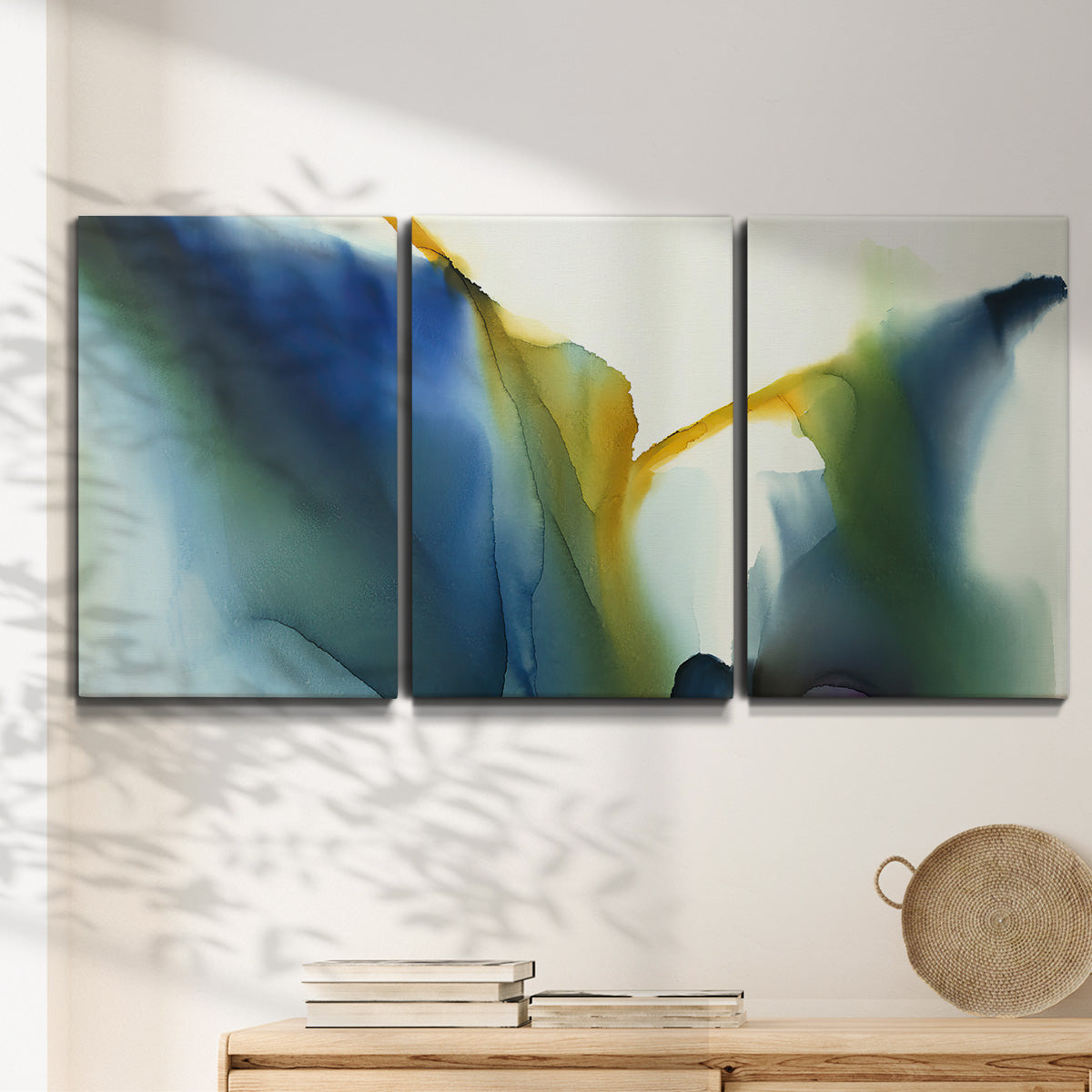 Three-panel canvas wall art featuring soft abstract mask like forms, displayed in a minimalist living room above a console table.