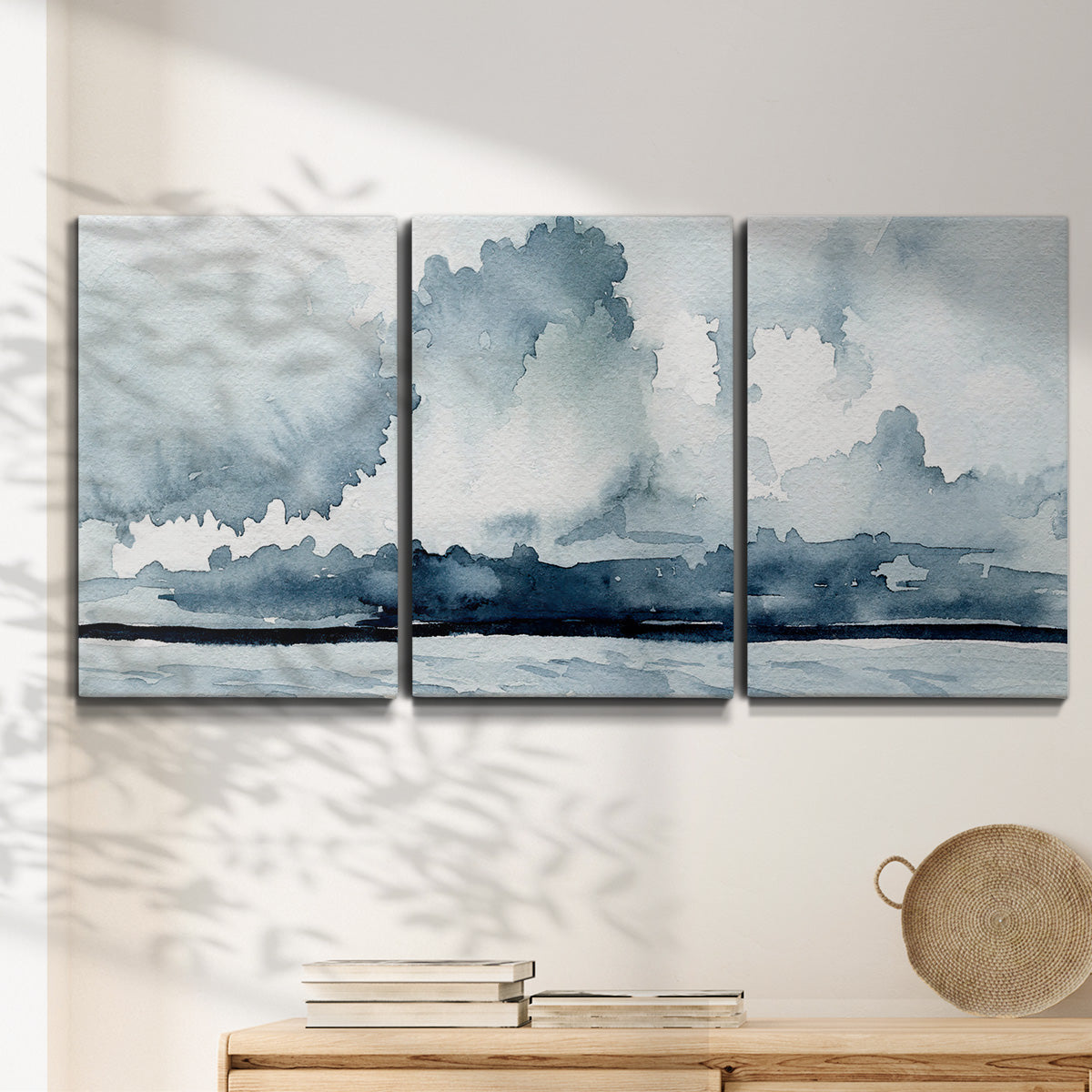 Three-panel canvas wall art featuring abstract rainstorm watercolor, displayed in a minimalist living room above a console table.