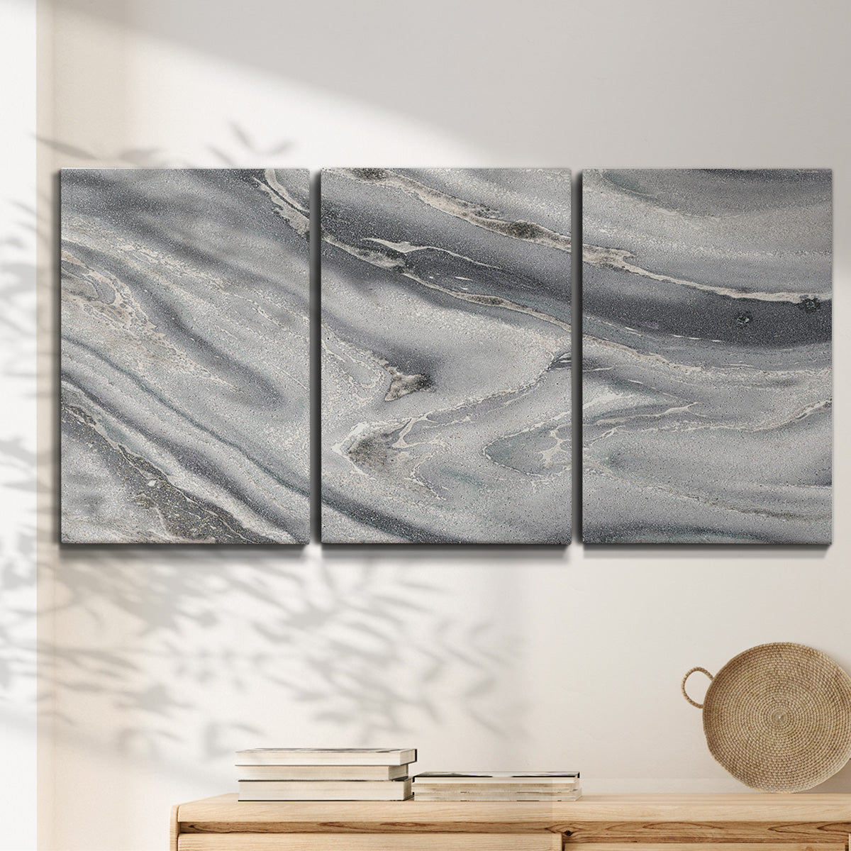 Three-panel canvas wall art featuring minimal monochrome abstract forms, displayed in a minimalist living room above a console table.