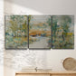 Three-panel canvas wall art featuring trees lining quiet creek, displayed in a minimalist living room above a console table.
