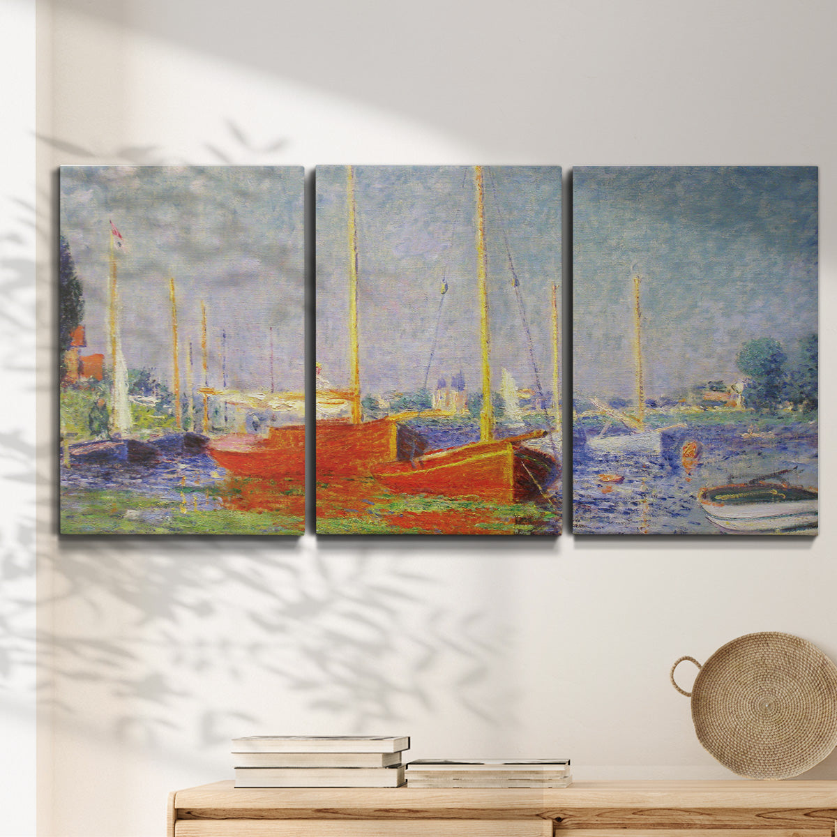 Three-panel canvas wall art featuring red boats along riverbank, displayed in a minimalist living room above a console table.